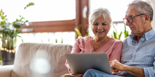 Couple sitting on sofa using laptop.